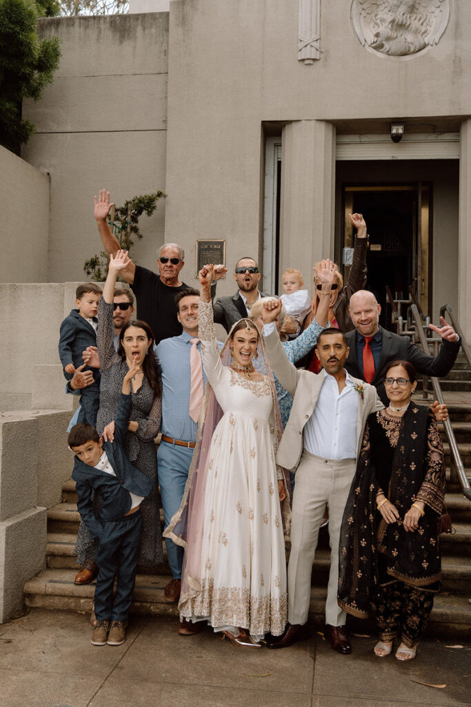 A newlywed couple with a small group of wedding guests celebrating and smiling 