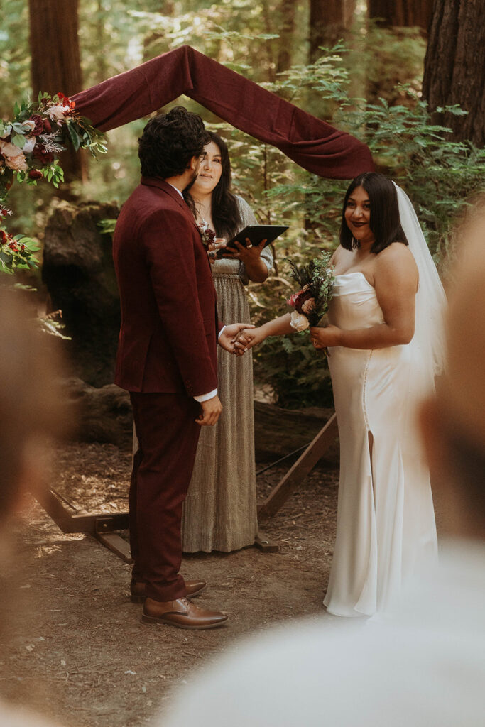 A couple holding hands as they say their vows at their wedding 