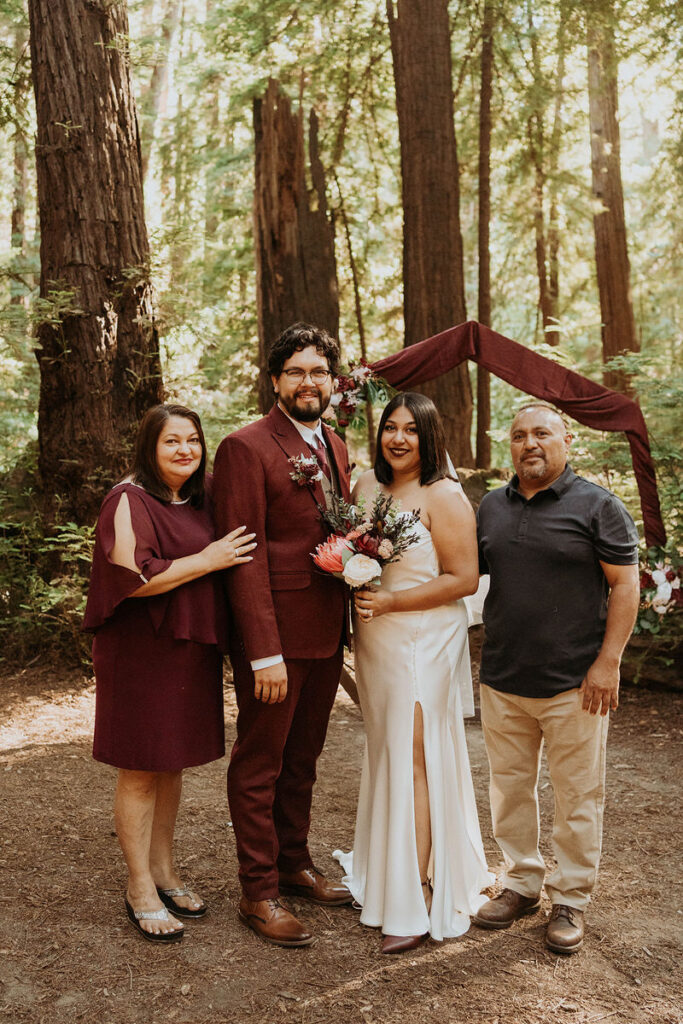 A newlywed couple standing with their parents and smiling 