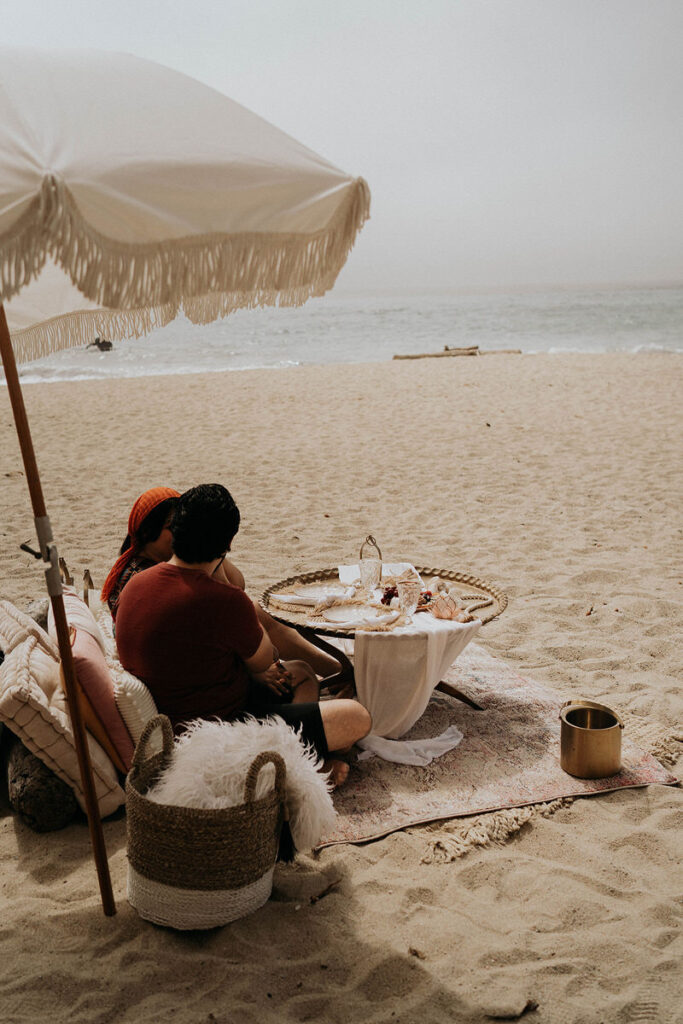 A couple sitting on the beach having a picnic 